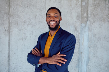 Portrait of a cheerful african american businessman smiling with crossed arms, showing confidence and success in his career