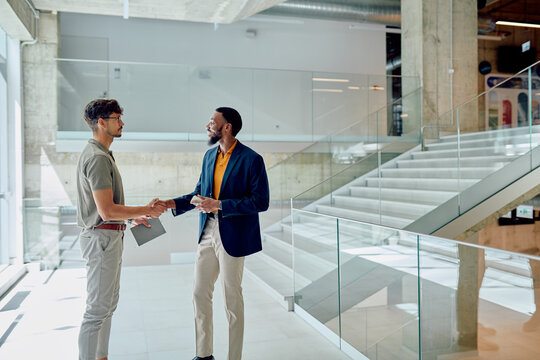 Two businessmen engaging in a handshake after a successful negotiation within a modern office building, highlighting collaboration and trust - Powered by Adobe