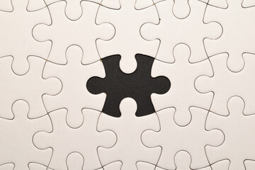 Puzzle de piezas completamente blancas con una pieza central ausente que revela un hueco negro en el centro de la imagen, simbolizando vac&iacute;o, ausencia o concepto incompleto