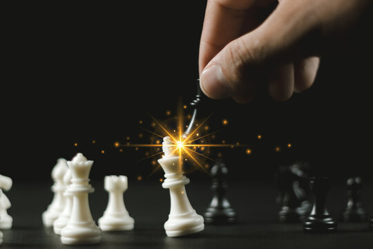 Businessman hand holding and moving white king chess figure with competitor to success play. Business management   competition and leadership concept.