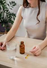 A woman holds omega-3 fish oil capsules. Healthy lifestyle, prevention and treatment of diseases. The woman takes and drinks dietary supplements and vitamins for skin, nails and hair. 