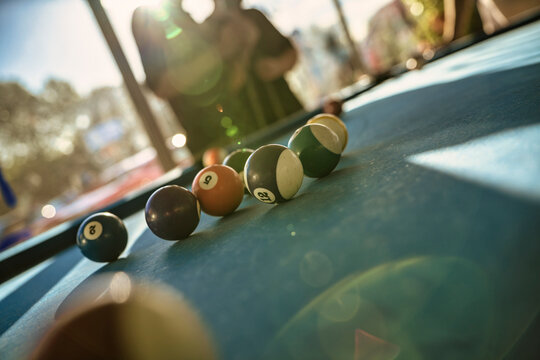 Billiard balls scattered on pool table in sunny game room