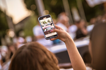 Woman recording live event with smartphone in blurred background