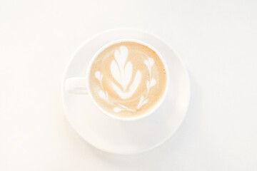 Latte coffee with artistic foam design served in a white cup and saucer