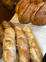 Freshly baked baguettes and sourdough loaves on display in a bakery shop setting
