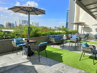 Outdoor seating area in a modern city with green grass and comfortable chairs on a sunny day