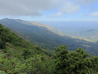 Naklejka premium Stunning panoramic view of lush mountains under a partly cloudy sky in a remote wilderness during the day