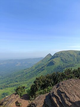 Breathtaking mountain view showcasing lush greenery and distant peaks under clear blue sky at dawn