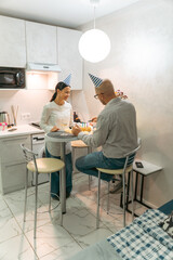 Couple Birthday Kitchen Celebration: Happy mature couple celebrates birthday in modern kitchen,...