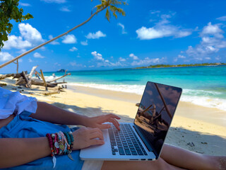 Nomad digital with laptop and running remotely with bright scenic view near poolside on the beach...