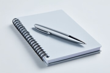 A spiral-bound notebook with a plain cover and a pen, isolated on a clean white background. Study, planning.