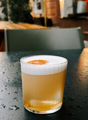 Craft cocktail with citrus garnish served at a cozy outdoor bar during late afternoon