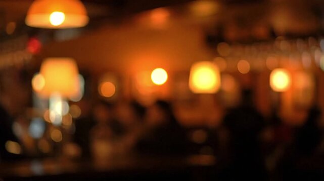 Blurred indoor scene with warm lighting featuring lamps and faint figures creating a soft abstract ambiance