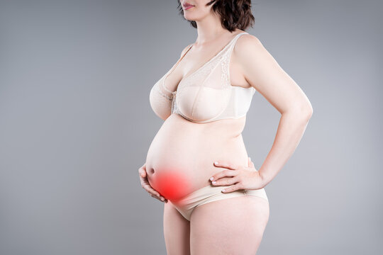 Pregnant woman with abdominal pain, risk of premature birth, gray background