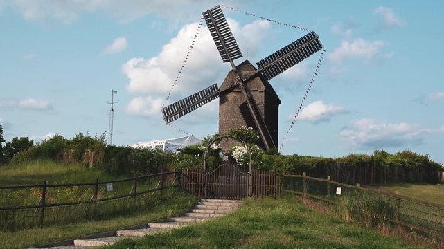 Historic German Wooden Windmill Fast Rotating Blades on a Scenic Summer Landscape with Blue Sky. Perfect for themes of rural life and sustainability.