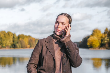 Young woman working remotely by a lake on a laptop. Digital nomad lifestyle, freedom, nature,...