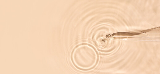 pipette serum in water on beige background ripples water drops natural sunlight