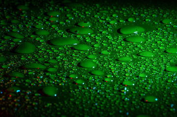 gotas de agua sobre fondo verde con destellos rojos  en un superficie plana