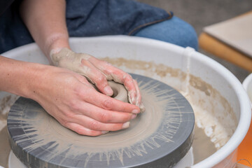 Woman making ceramics in pottery workshop. Close up of female potters hands making bowl. Woman...