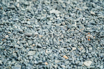 A textured surface filled with small, angular gray rocks, creating a natural and raw aesthetic. The stones are densely packed, offering a rough, uneven, and captivating visual texture.