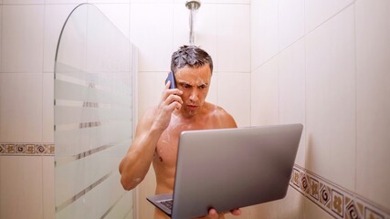 Busy man holding laptop and talking on phone while showering