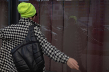 A person who is wearing a bright yellow beanie and carrying a black backpack is actively pointing...