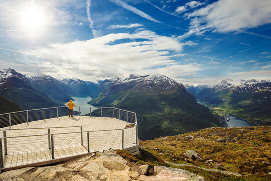 Aerial view from Mount Hoven to the picturesque valley and lake Lovatnet on a cloudy day. A man stands on the viewing platform and looks at the breathtaking view. Loen, Norway, Europe.
