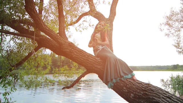 Girls in mermaid costumes dancing on the shore near the water at sunset