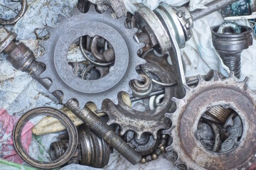 pile of old black grey iron bicycle parts with bushings sprockets and bearings in a box