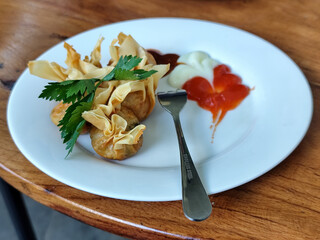 Crispy fried dumplings served with celery leaves, as well as chili, tomato and mayonnaise sauce...