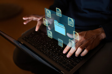 Person using laptop with digital folder and document icons floating above the keyboard area