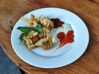 Crispy fried dumplings served with celery leaves, as well as chili, tomato and mayonnaise sauce...