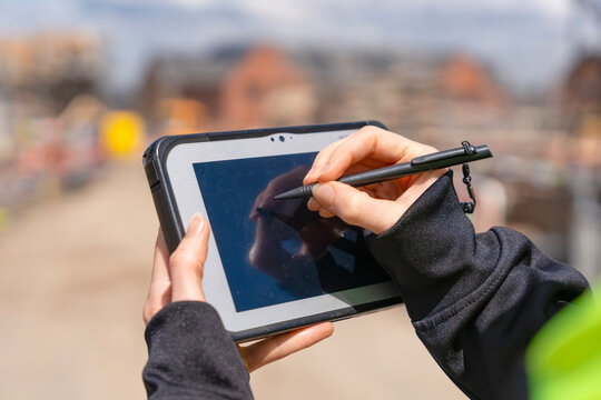 Close-up of woman construction manager useing rugged tablet to record data on construction site