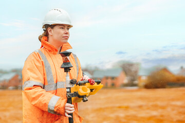 Female builder land surveyor working under rain on construction site