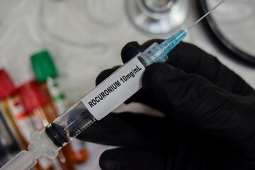 Rocuronium 10ml vaccination drug syringe in black gloved hands. Medical concept