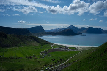 White sand and turquoise blue water.  Small waves of turquoise blue water wash gently across the white sand while mountain peaks rise into the blue sky above.  Typically the words arctic and beach are