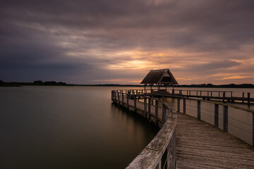 Obraz premium The beautiful Hemmelsdorfer See, with its long and large jetty at sunrise.