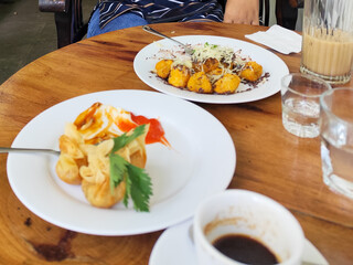 Serve various snacks and drinks on a warm wooden table, in an outdoor cafe. with natural blur.