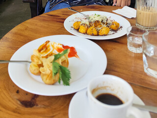 Serve various snacks and drinks on a warm wooden table, in an outdoor cafe. with natural blur.