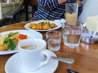 Serve various snacks and drinks on a warm wooden table, in an outdoor cafe. with natural blur.