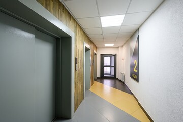 Hallway with elevators, textured walls, and geometric floor. A modern, clean, interior space