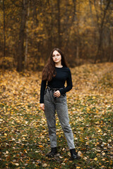 girl in jeans and a black sweater in the forest in autumn