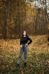 girl in jeans and a black sweater in the forest in autumn