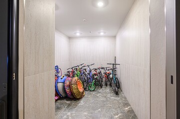 storage room with bikes, scooters, and snow tubes. Walls are tiled and a gray floor