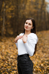 Girl in jeans and a white sweater in the forest in autumn