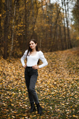 Girl in jeans and a white sweater in the forest in autumn