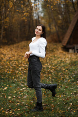 Girl in jeans and a white sweater in the forest in autumn