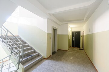 building interior showcasing a staircase, elevator, and hallway.  The walls are two-toned in white and light green