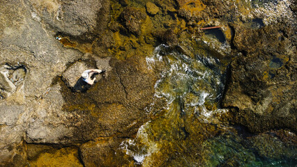 Man Sitting on Coastal Rocks by the Sea
