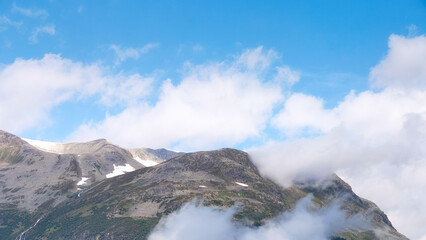 Clarity in the heights — the rugged slopes above Geirangerfjord meet drifting clouds and...